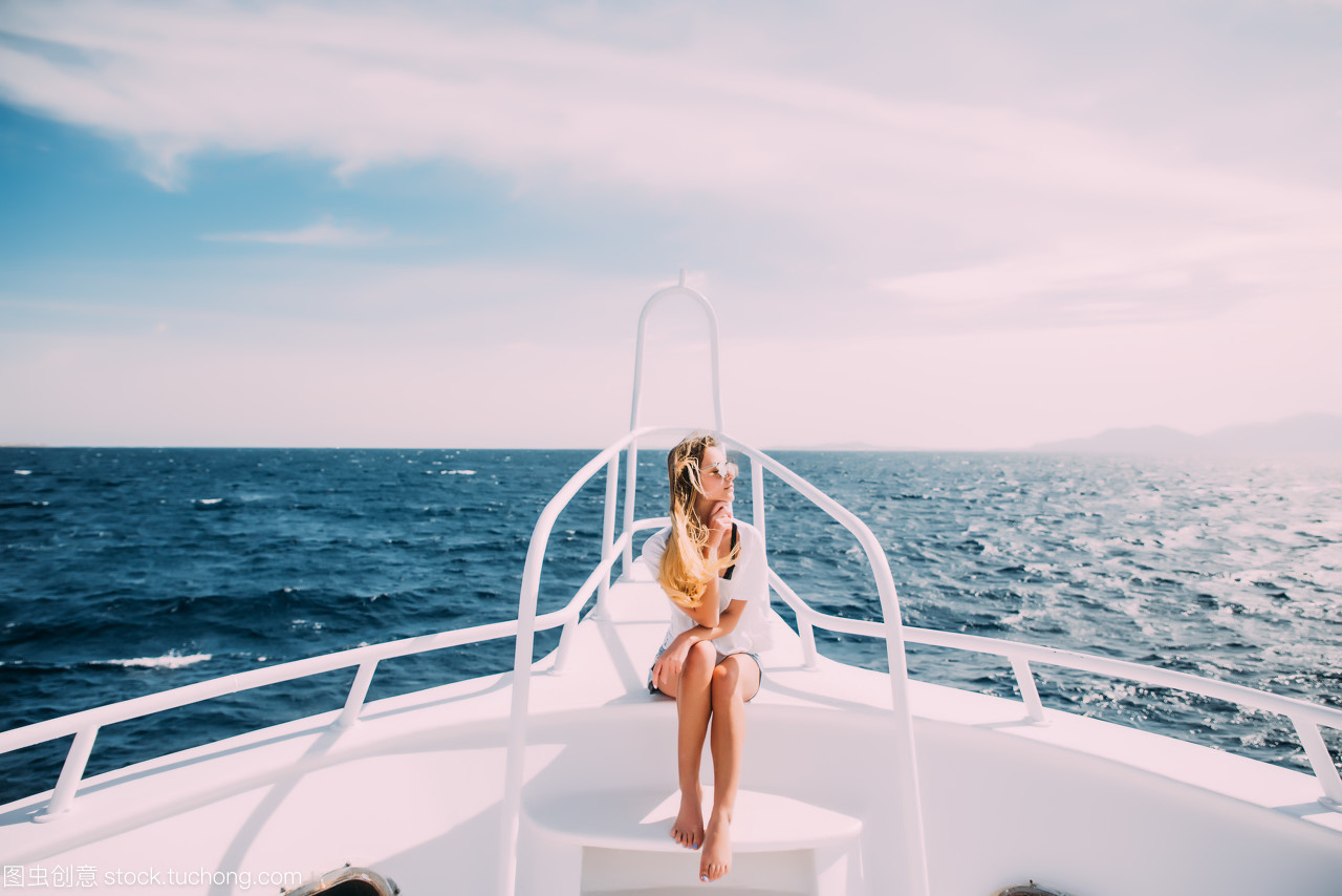 女人放松的白色游艇在海上的鼻子。暑假的时候